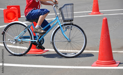Ecolier à vélo sur un circuit avec des plots oranges, apprentissage du code le route, exercice de prévention routière enfants	 photo