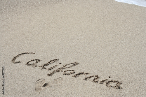 Conceptual handwritten text California in sand