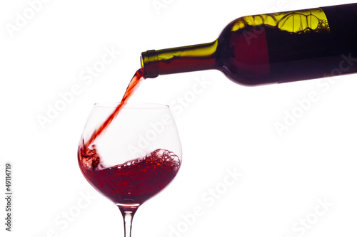Rotwein wird in ein Weinglas eingegossen photo