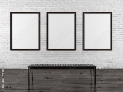 Brick wall with three empty frames and bench