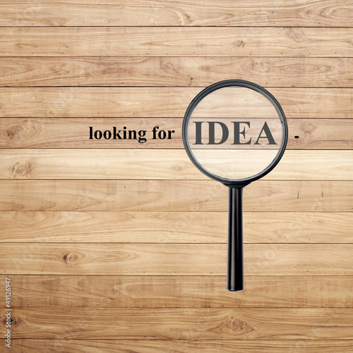 Looking for idea with magnify glass on Brown wood background © 2nix