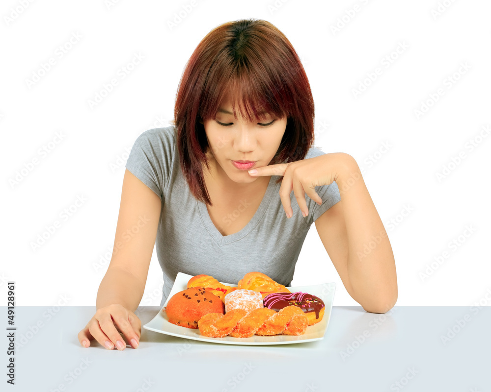 Isolated young asian woman with a donuts on the table