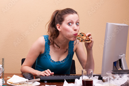 junge frau isst Pizza am Arbeitsplatz