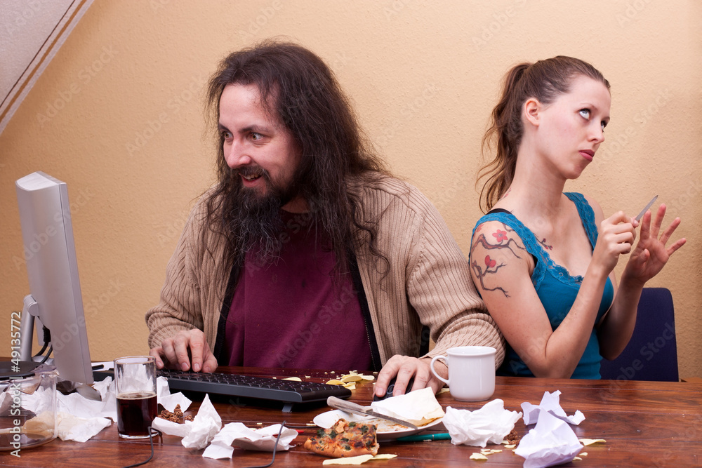 Langhaariger Nerd am Computer mit genervter schönen Frau Langhaariger Nerd am Computer mit genervter schönen Frau