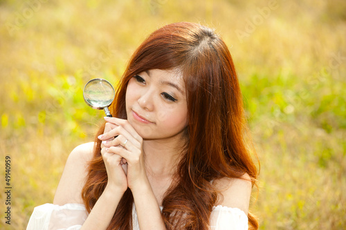 Pretty Asian woman happy with the magnifying glass . photo