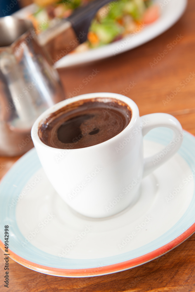 Cup of turkish coffee with salad in background Cup of turkish coffee with salad in background