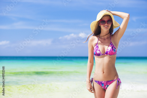 Beautiful young woman standing on the beach enjoying the sun
