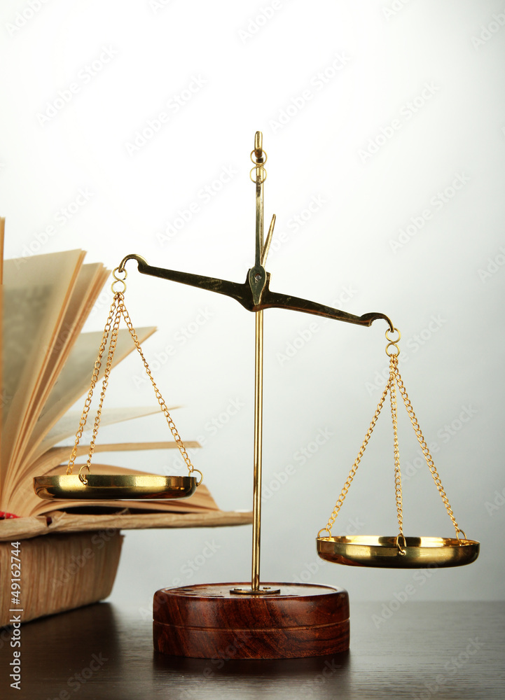 Gold scales of justice and books on grey background Gold scales of justice and books on grey background