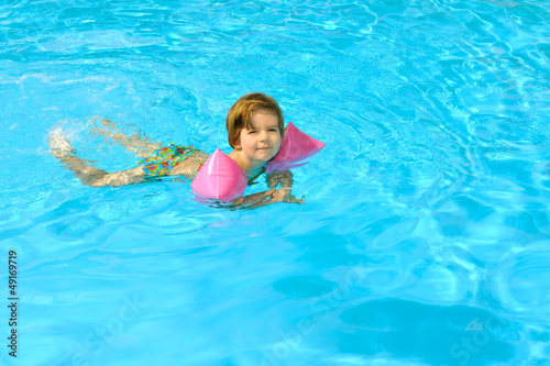 Toddler girl learning to swim in the swimming pool