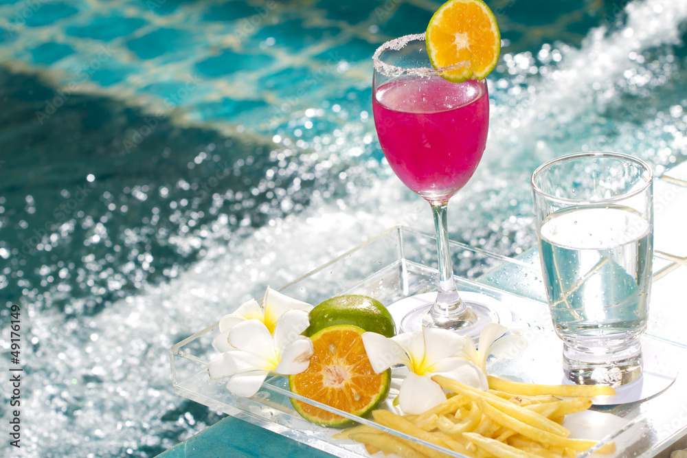 Pink cocktail decorated with orange by the Jacuzzi pool