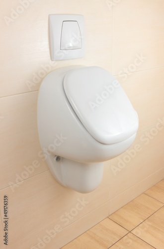 white urinal on beige tiled wall