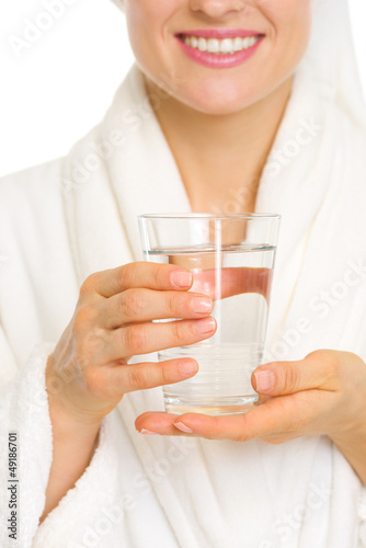 Closeup on smiling young woman in bathrobe with glass of water