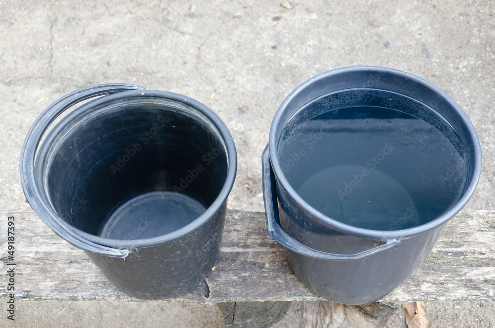 Two plastic buckets, one full, one empty