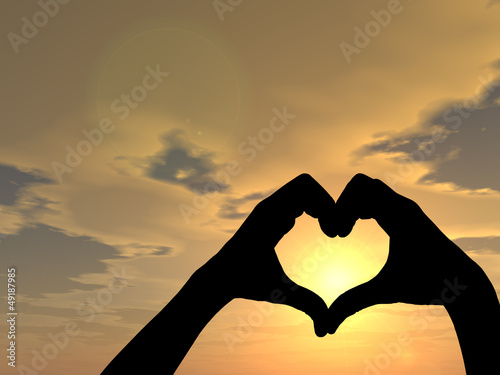 Conceptual heart shape human hand silhouette over sky at sunset