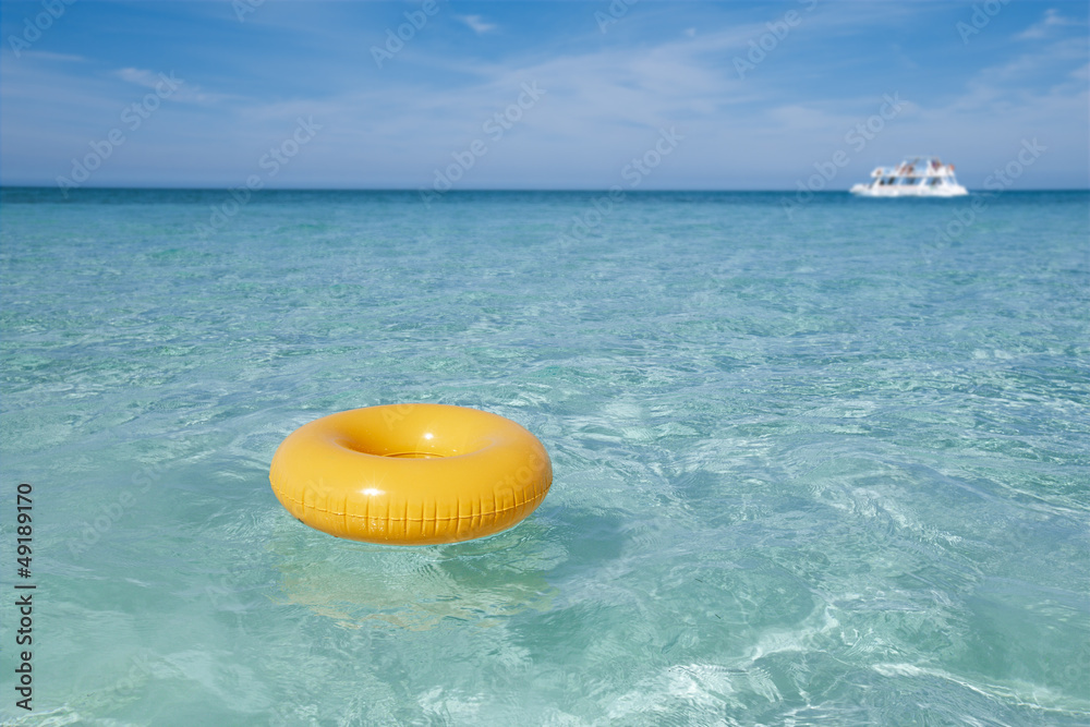 Naklejka premium floating ring on blue clear sea with white boat, shallow dof