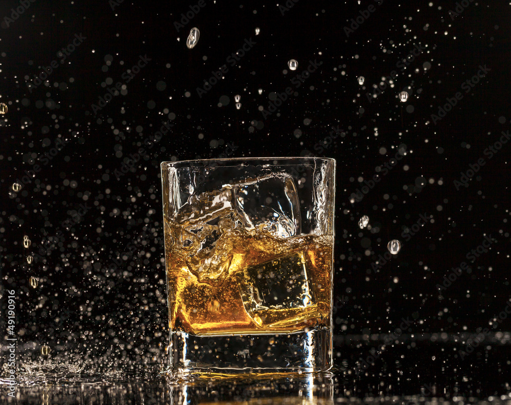 Whiskey splashing around glass, isolated on black background Whiskey splashing around glass, isolated on black background