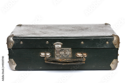 Old green suitcase with metal corners lying on the floor