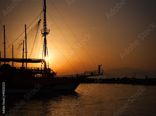 Sailing ship silhouetted against amber setting sun