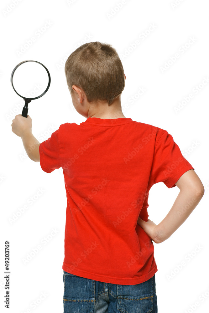 Back viev of 6 years boy looking through the magnifying glass Back viev of 6 years boy looking through the magnifying glass