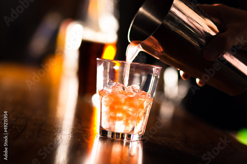 Hands of a bartender pouring a drink into a glass photo