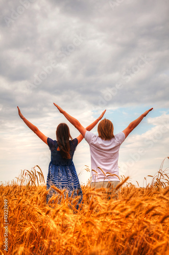 Obraz na płótnie Couple staying with raised hands at a wheat field w salonie