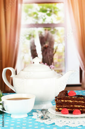 Teapot  cup of tea and delicious cake on window background