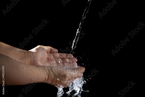 hand and pouring water on black background