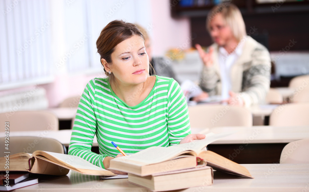 Young woman studying at desk with lots of books Young woman studying at desk with lots of books