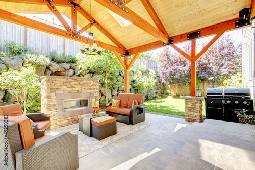 Exterior covered patio with fireplace and furniture.