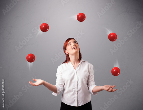 young girl standing and juggling with red balls