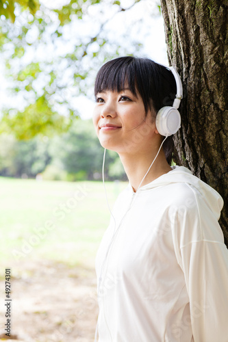 attractive asian woman listening music in the park