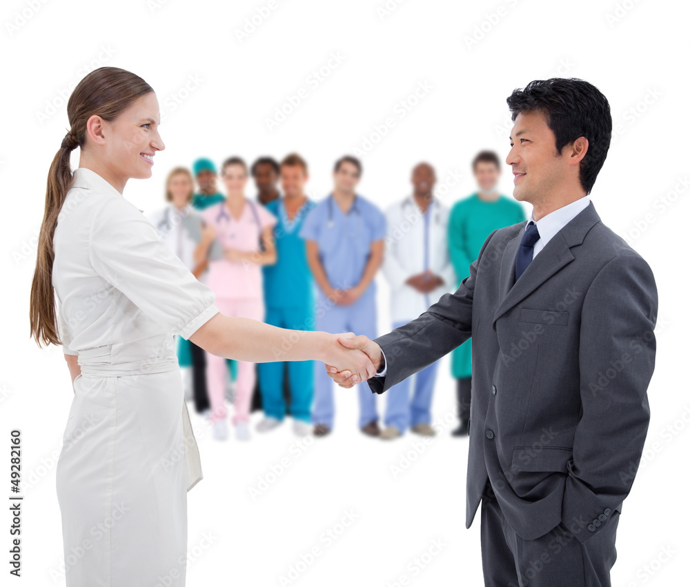 Business people shaking hands with medical staff in background Business people shaking hands with medical staff in background