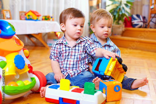 two cute baby toddlers playing in nursery room
