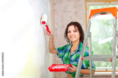 Happy woman paints wall photo