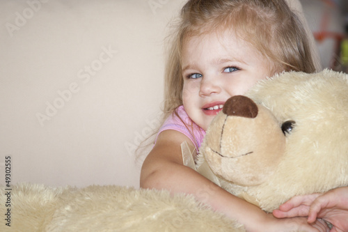Portrait of an adorable toddler girl hugging a teddy bear