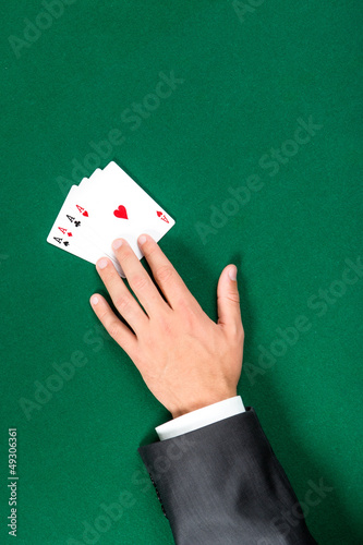 Hand with aces on the green table. Addiction to the gambling