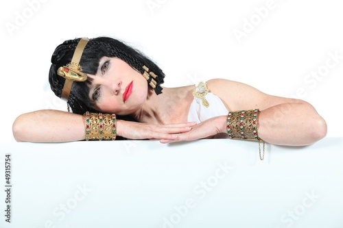 Woman dressed as Cleopatra leaning on a board for text