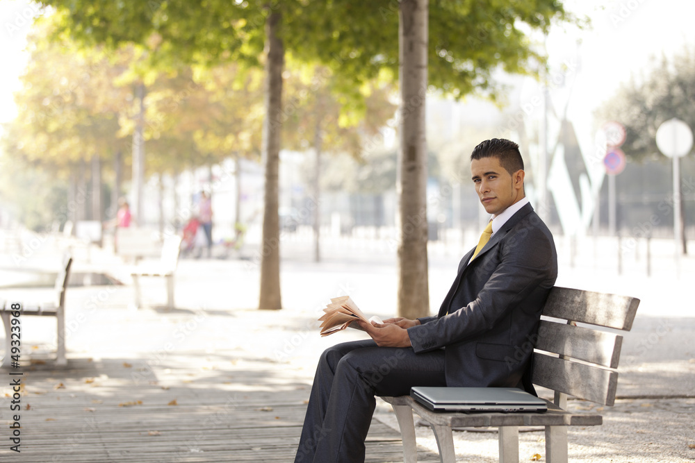 Businessman reading his newspaper next to his office building