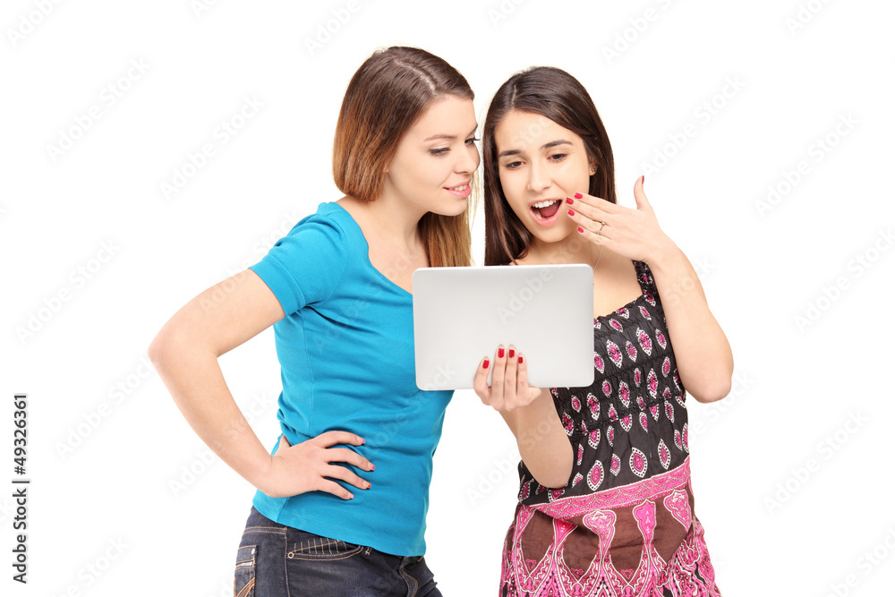 Two young female friends standing close together and looking at Two young female friends standing close together and looking at