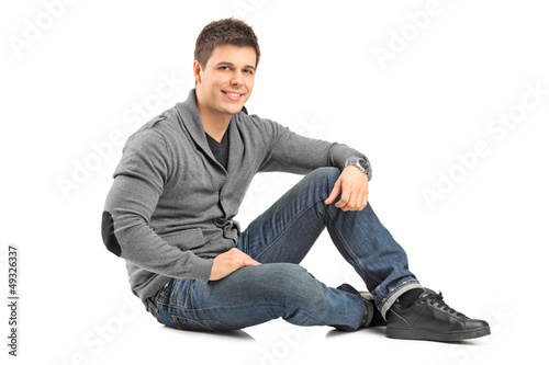 Smiling guy sitting on a floor and looking at camera