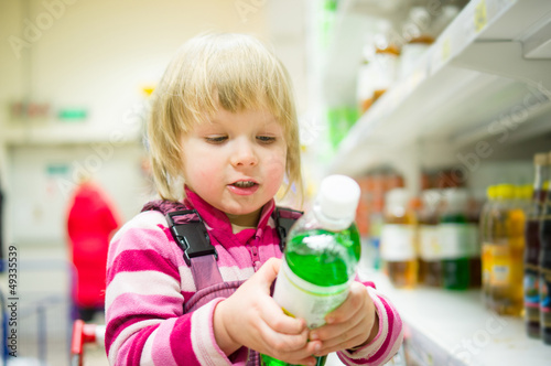 Adorable girl select bottle of soda drink stay in shopping cart