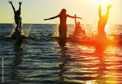 Silhouettes of people jumping in ocean