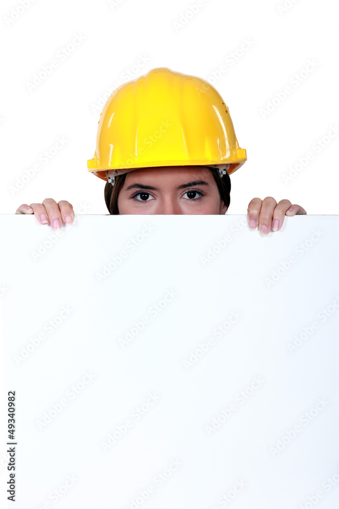 A female construction worker hiding behind a billboard. A female construction worker hiding behind a billboard.