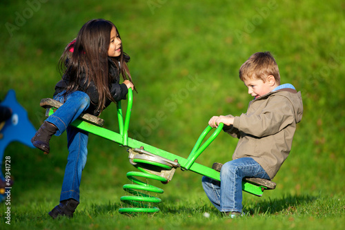 Bild auf Leinwand enfants jouant a la balançoire dans un parc de jeu