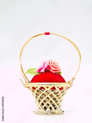 A miniature metalic wicker decorated by roses on a red velvet is