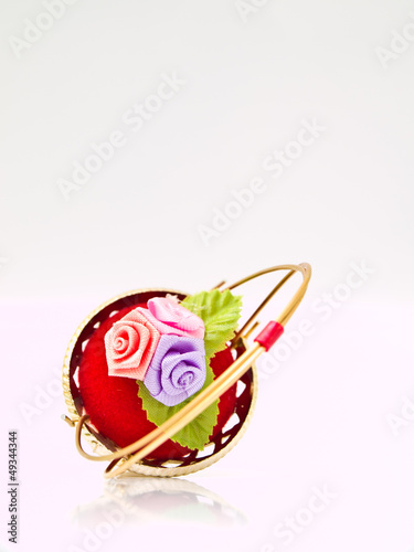 A miniature metalic wicker decorated by roses on a red velvet is