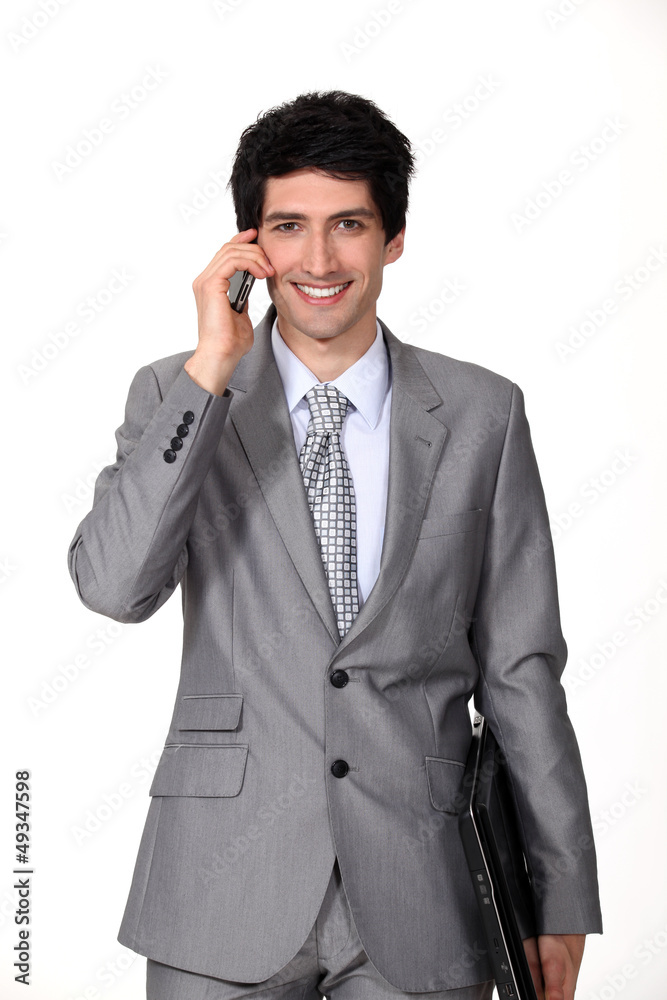 A businessman holding a phone and a laptop. A businessman holding a phone and a laptop.