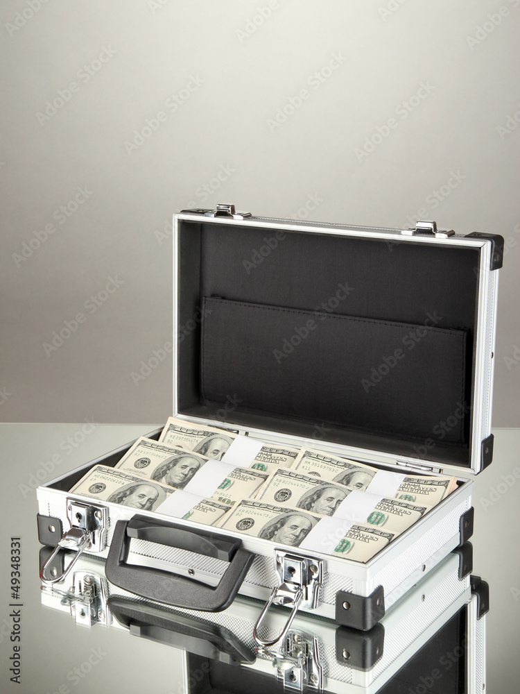 Suitcase with 100 dollar bills on grey background Suitcase with 100 dollar bills on grey background
