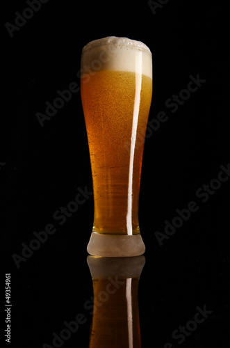 Glass with beer served on the table with black background.