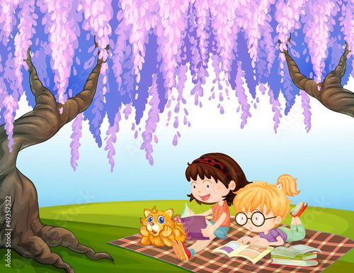 Girls reading at the park with a cat